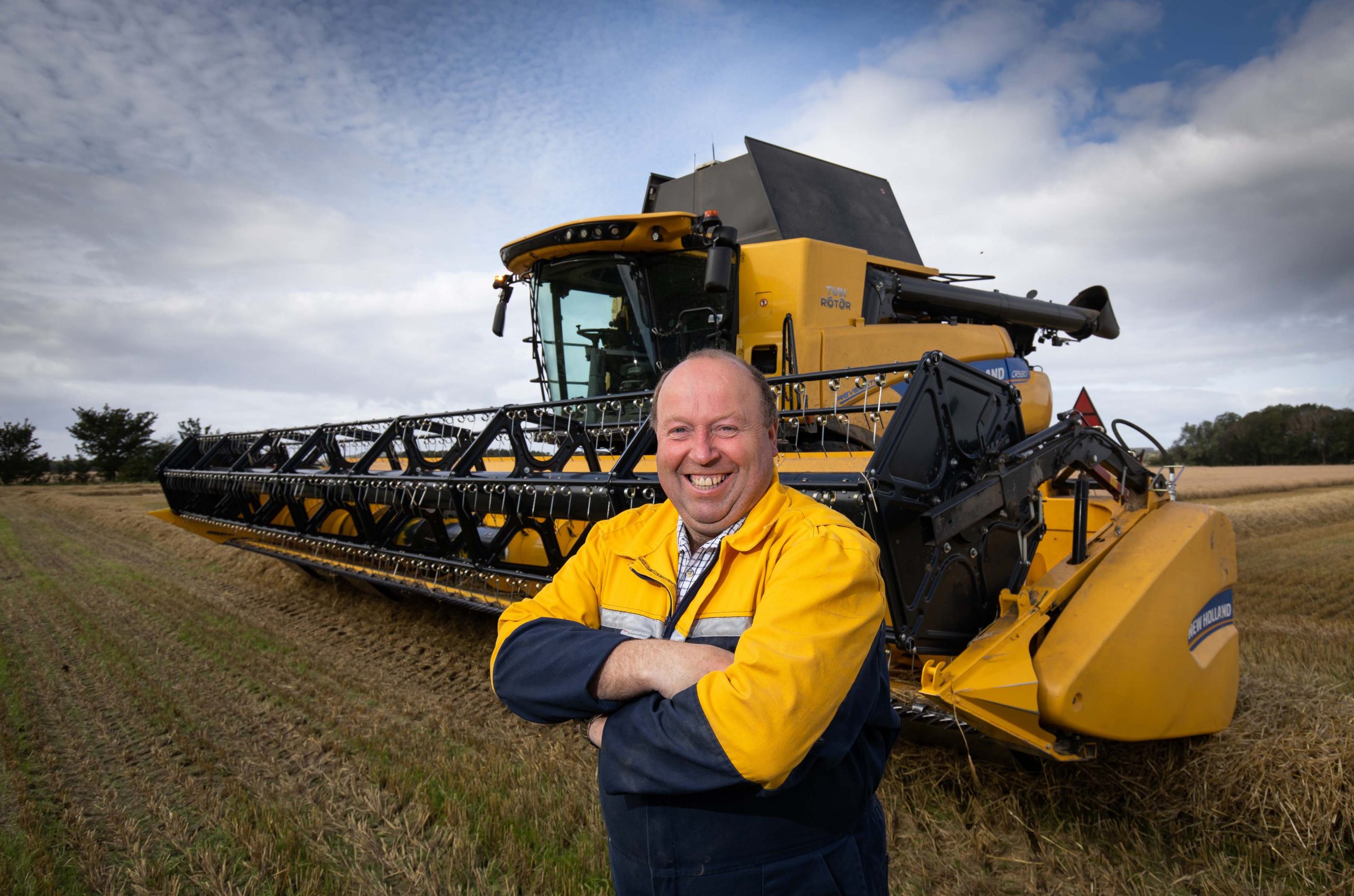 One of Barley Malt farmers in the UK, stands beside hos combine harvester in the field after harvest.
