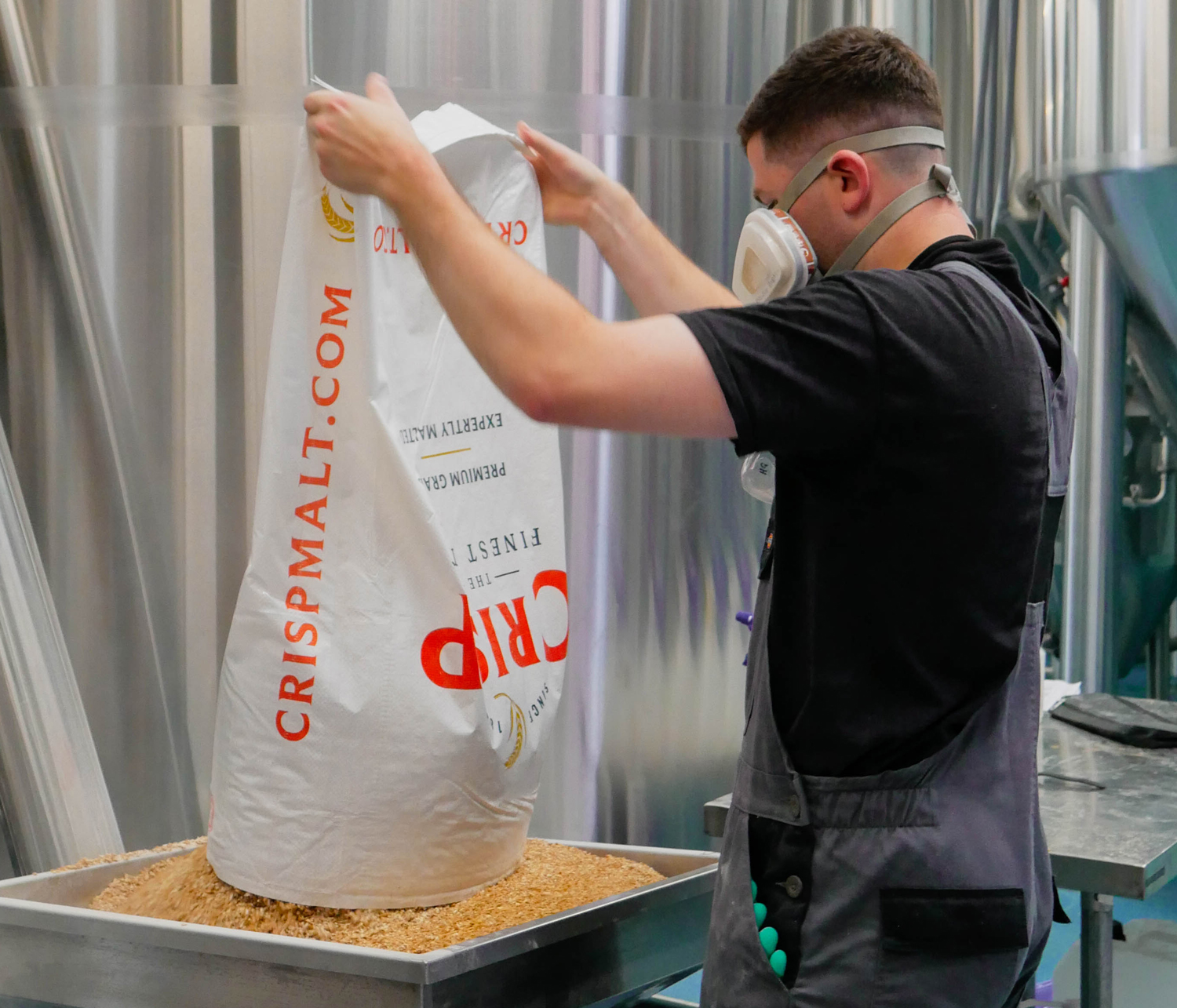Sam Fraise from Attic Brewery tips out malt from a Crisp branded bag ready to be milled for brewing.